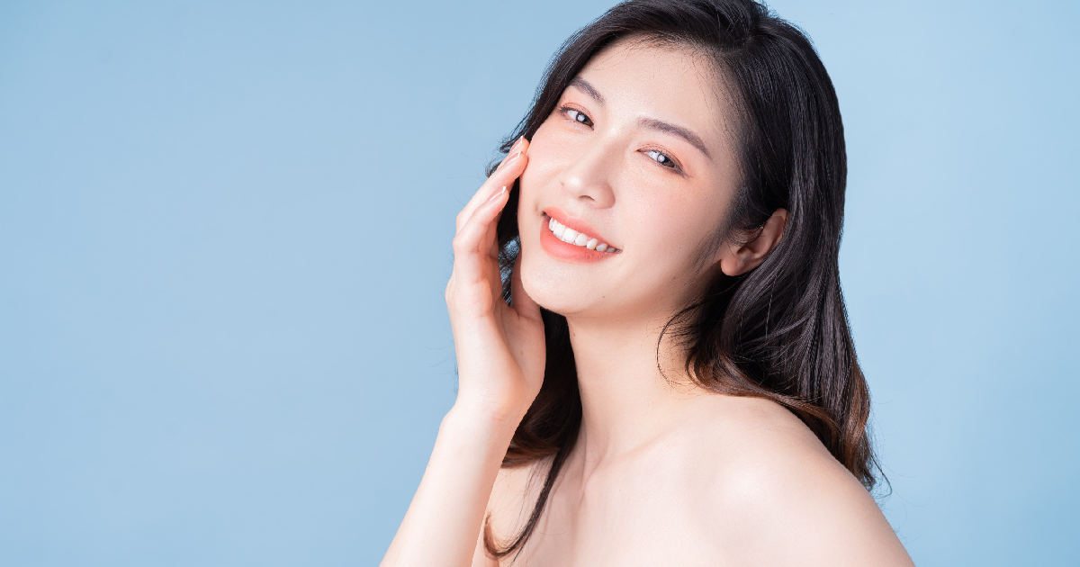 Smiling woman with radiant skin touching her face after Skin Rejuvenation in Austin TX