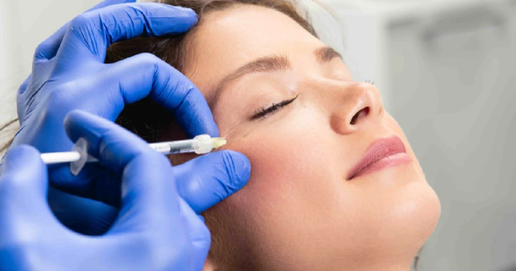 woman receiving a dermal filler injection near her cheek administered by a professional wearing blue medical gloves in Austin TX 1