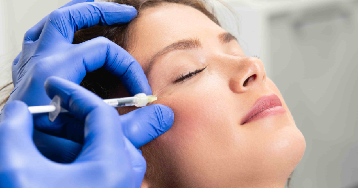 woman receiving a dermal filler injection near her cheek, administered by a professional wearing blue medical gloves in Austin, TX